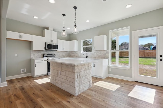 109 Creekside Dr, Bastrop, TX 78602 - kitchen featuring appliances with stainless steel finishes, light countertops, white cabinets, decorative backsplash, and a kitchen island