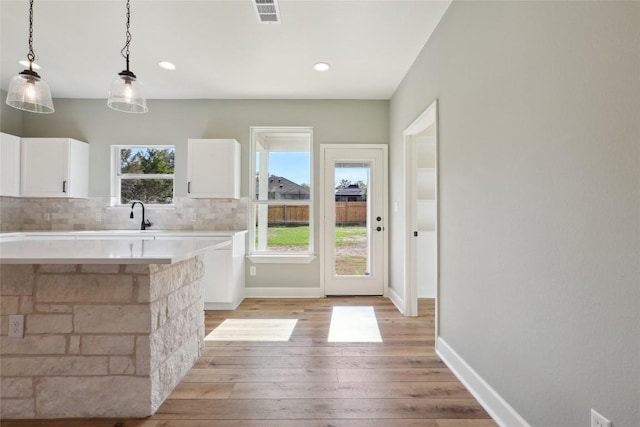 kitchen featuring pendant lighting, light hardwood / wood-style floors, white cabinetry, and plenty of natural light