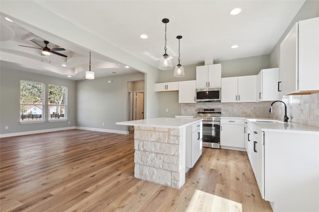 kitchen with a center island, hanging light fixtures, stainless steel appliances, light hardwood / wood-style floors, and white cabinets