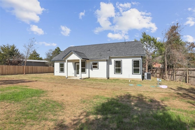 rear view of house with cooling unit and a lawn