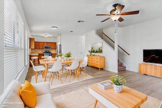 living room featuring ceiling fan, light hardwood / wood-style floors, and sink