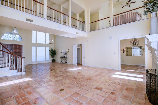 unfurnished living room featuring ceiling fan, light tile patterned floors, and a high ceiling