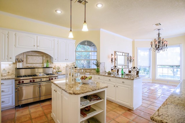 kitchen with white cabinets, tasteful backsplash, high end stainless steel range oven, and hanging light fixtures