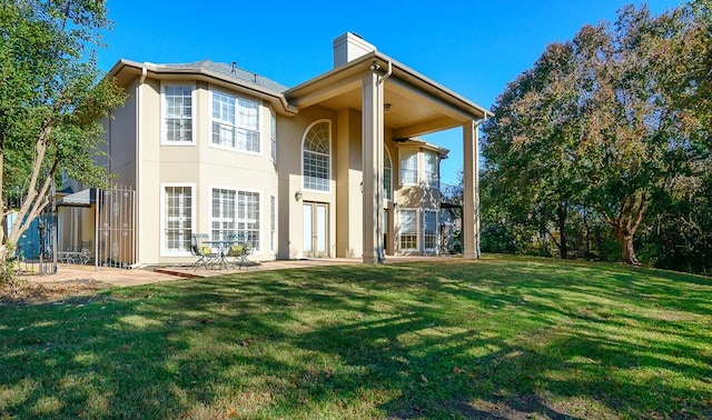 back of house with a lawn and a patio