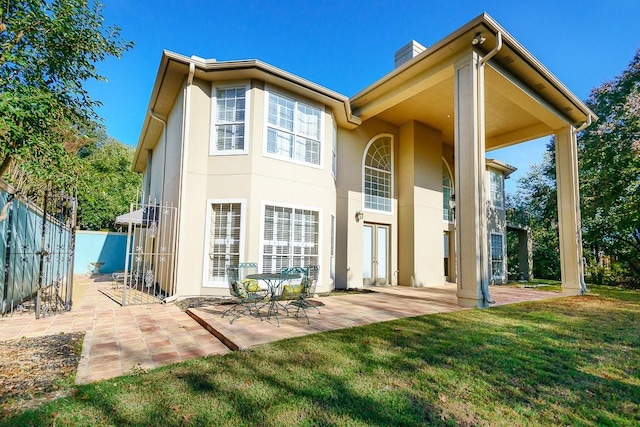 back of house with a lawn and a patio