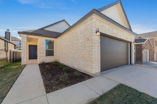 12521 Orchard Grove Ln, Manor, TX 78653 - view of front of house featuring a garage, concrete driveway, stone siding, and roof with shingles