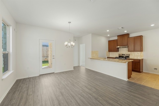 kitchen with stainless steel electric range oven, plenty of natural light, hanging light fixtures, and light wood-type flooring