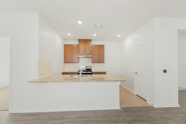 kitchen with light stone countertops, sink, kitchen peninsula, light hardwood / wood-style floors, and stainless steel range with electric cooktop