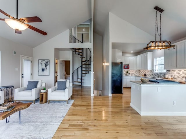 kitchen featuring decorative backsplash, light hardwood / wood-style floors, black fridge, and white cabinetry