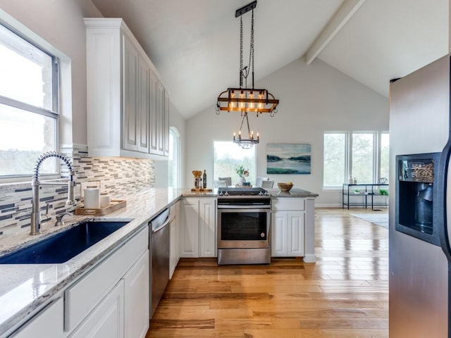 kitchen with sink, stainless steel appliances, decorative light fixtures, white cabinets, and light wood-type flooring