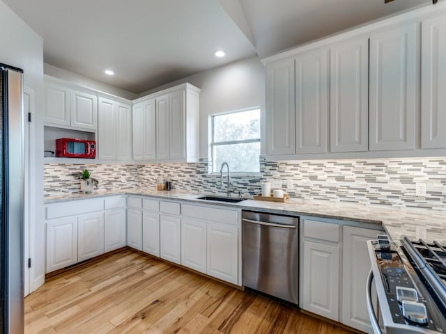 kitchen featuring backsplash, white cabinets, sink, light hardwood / wood-style flooring, and appliances with stainless steel finishes