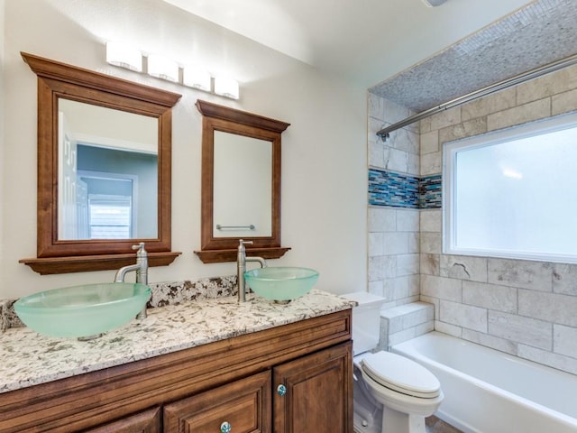 full bathroom featuring vanity, tiled shower / bath combo, and toilet