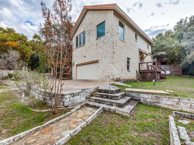 view of side of property with a lawn, a deck, and a garage