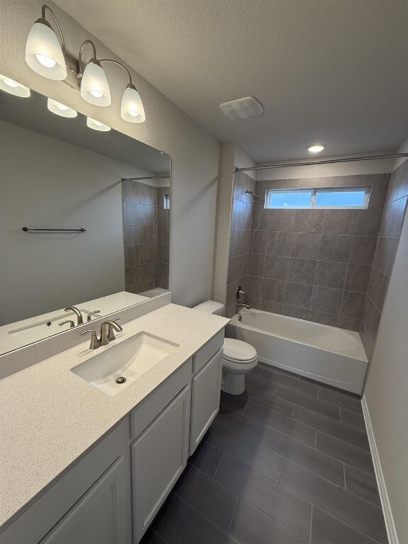 full bathroom featuring tiled shower / bath combo, toilet, a textured ceiling, and vanity