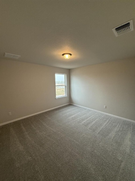 carpeted spare room featuring a textured ceiling