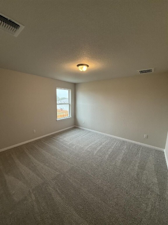 carpeted spare room featuring a textured ceiling