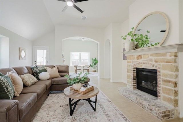 living room with ceiling fan, a fireplace, lofted ceiling, and light wood-type flooring