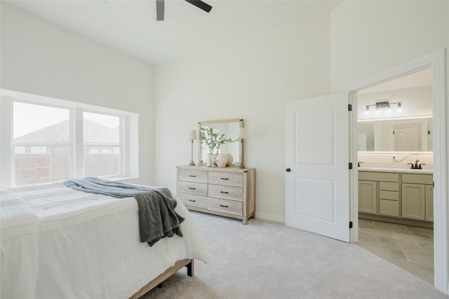 bedroom featuring a high ceiling, connected bathroom, light colored carpet, and ceiling fan