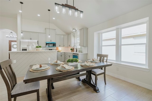 dining area with lofted ceiling, sink, and an inviting chandelier