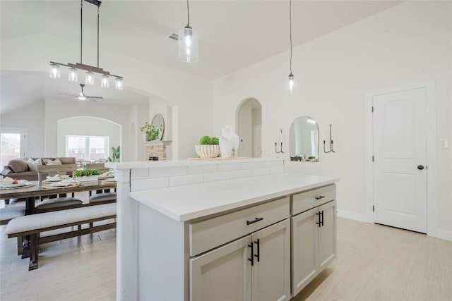 kitchen featuring a center island, lofted ceiling, hanging light fixtures, light hardwood / wood-style flooring, and ceiling fan