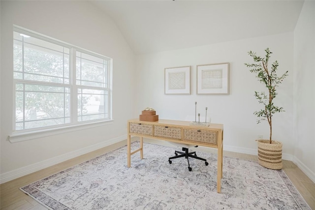 home office with light hardwood / wood-style floors and lofted ceiling