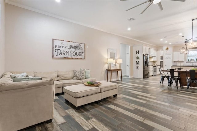 living room with dark hardwood / wood-style floors, ornamental molding, and ceiling fan with notable chandelier