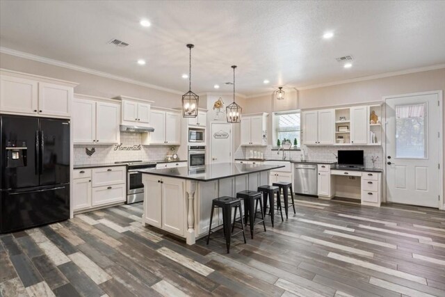 kitchen featuring appliances with stainless steel finishes, white cabinetry, hanging light fixtures, and a kitchen island