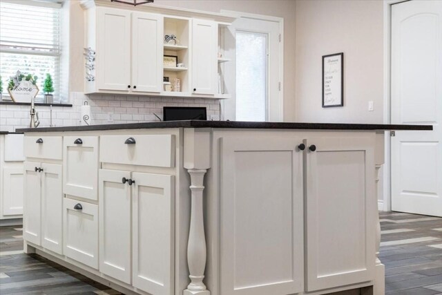 kitchen featuring dark hardwood / wood-style flooring, white cabinetry, and backsplash