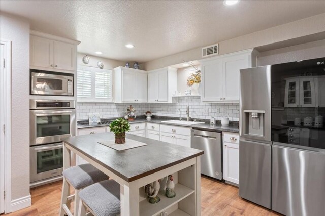 kitchen with white cabinetry, sink, stainless steel appliances, and light hardwood / wood-style floors