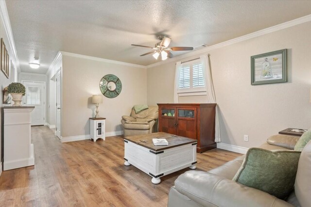 living room with hardwood / wood-style flooring, ceiling fan, crown molding, and a textured ceiling