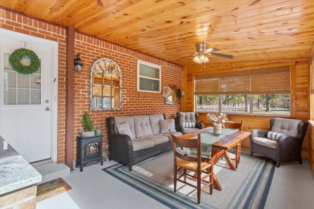 living room featuring ceiling fan, concrete flooring, brick wall, and wooden ceiling