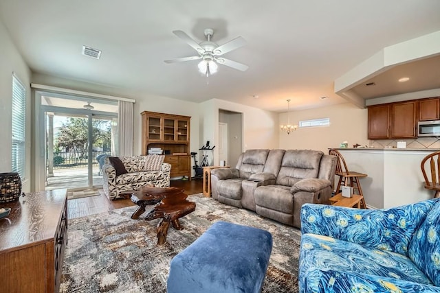 living room with hardwood / wood-style floors and ceiling fan with notable chandelier