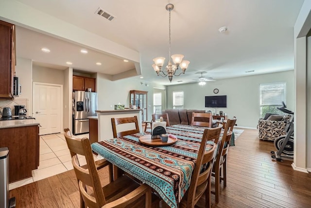 dining space with plenty of natural light, ceiling fan with notable chandelier, and light hardwood / wood-style flooring