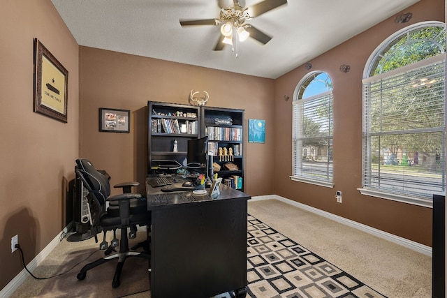 carpeted office space featuring ceiling fan