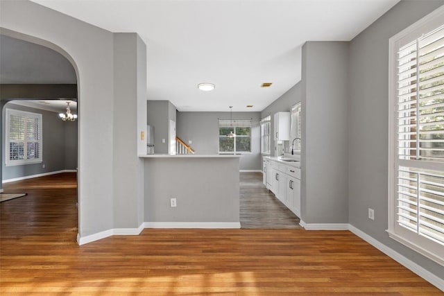 kitchen with an inviting chandelier, white cabinets, sink, light hardwood / wood-style flooring, and kitchen peninsula