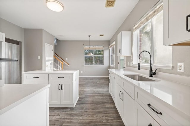 kitchen featuring stainless steel refrigerator, white cabinetry, sink, dark wood-type flooring, and decorative light fixtures