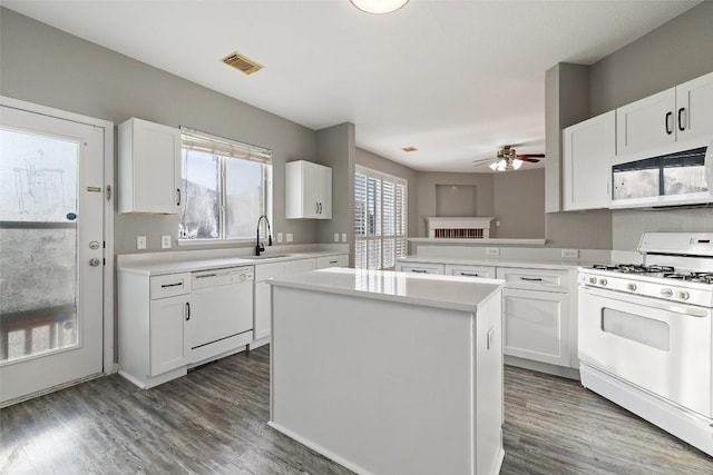 kitchen featuring white cabinetry, dark hardwood / wood-style floors, kitchen peninsula, white appliances, and a kitchen island