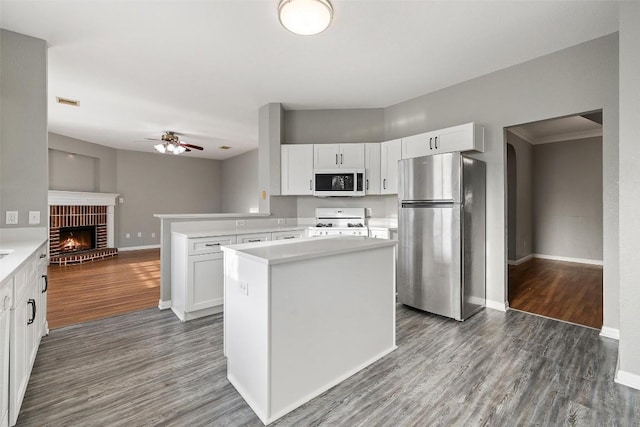 kitchen featuring kitchen peninsula, white cabinets, dark hardwood / wood-style floors, and white appliances