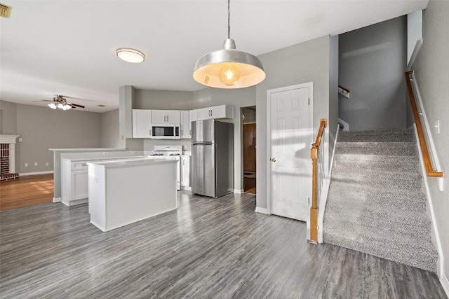 kitchen featuring white cabinets, stainless steel refrigerator, hanging light fixtures, and dark wood-type flooring