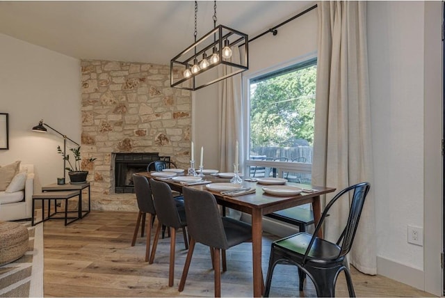 dining area with a fireplace, light hardwood / wood-style floors, and vaulted ceiling