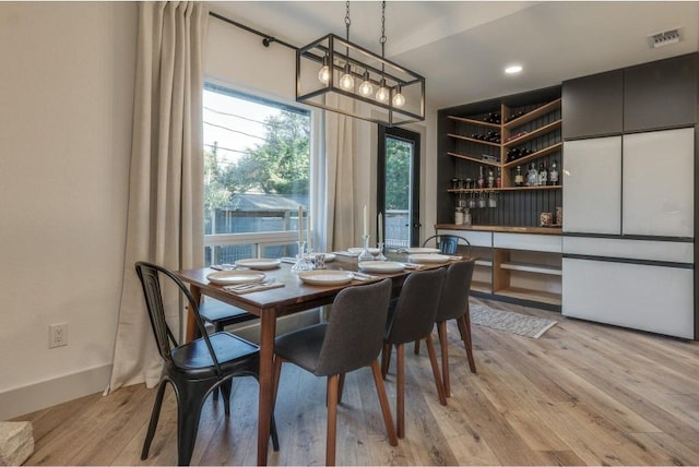 dining space with light hardwood / wood-style flooring and bar