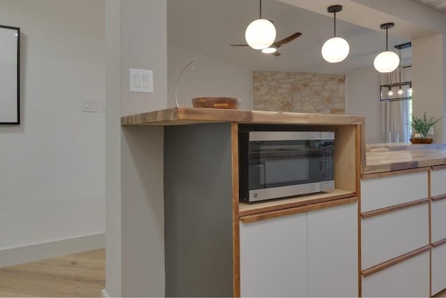 kitchen with white cabinetry, hanging light fixtures, light hardwood / wood-style floors, and vaulted ceiling