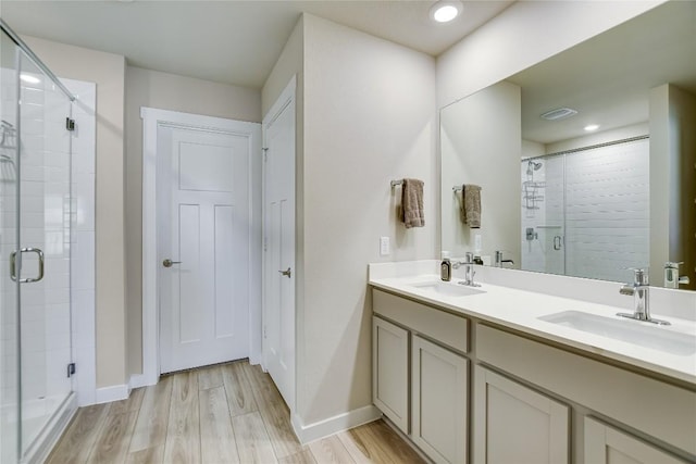 bathroom featuring hardwood / wood-style flooring, vanity, and a shower with shower door