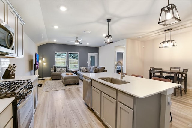 kitchen with pendant lighting, sink, a kitchen island with sink, and stainless steel appliances