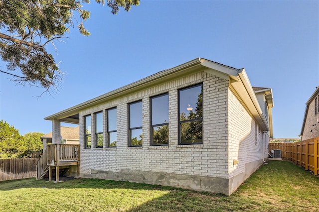 view of side of property featuring a yard and central AC