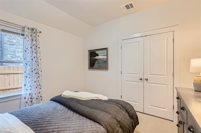 bedroom featuring light carpet, vaulted ceiling, and a closet