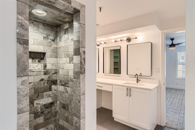 bathroom with a tile shower, ceiling fan, tile patterned floors, and vanity