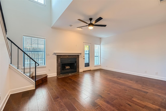 unfurnished living room with ceiling fan, ornamental molding, a tile fireplace, and dark hardwood / wood-style floors