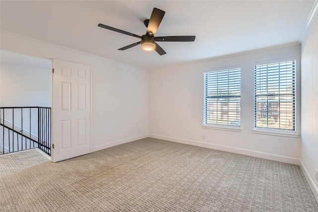 empty room featuring ceiling fan, light colored carpet, and crown molding