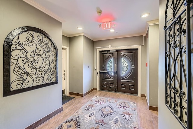 entryway with light hardwood / wood-style floors and crown molding